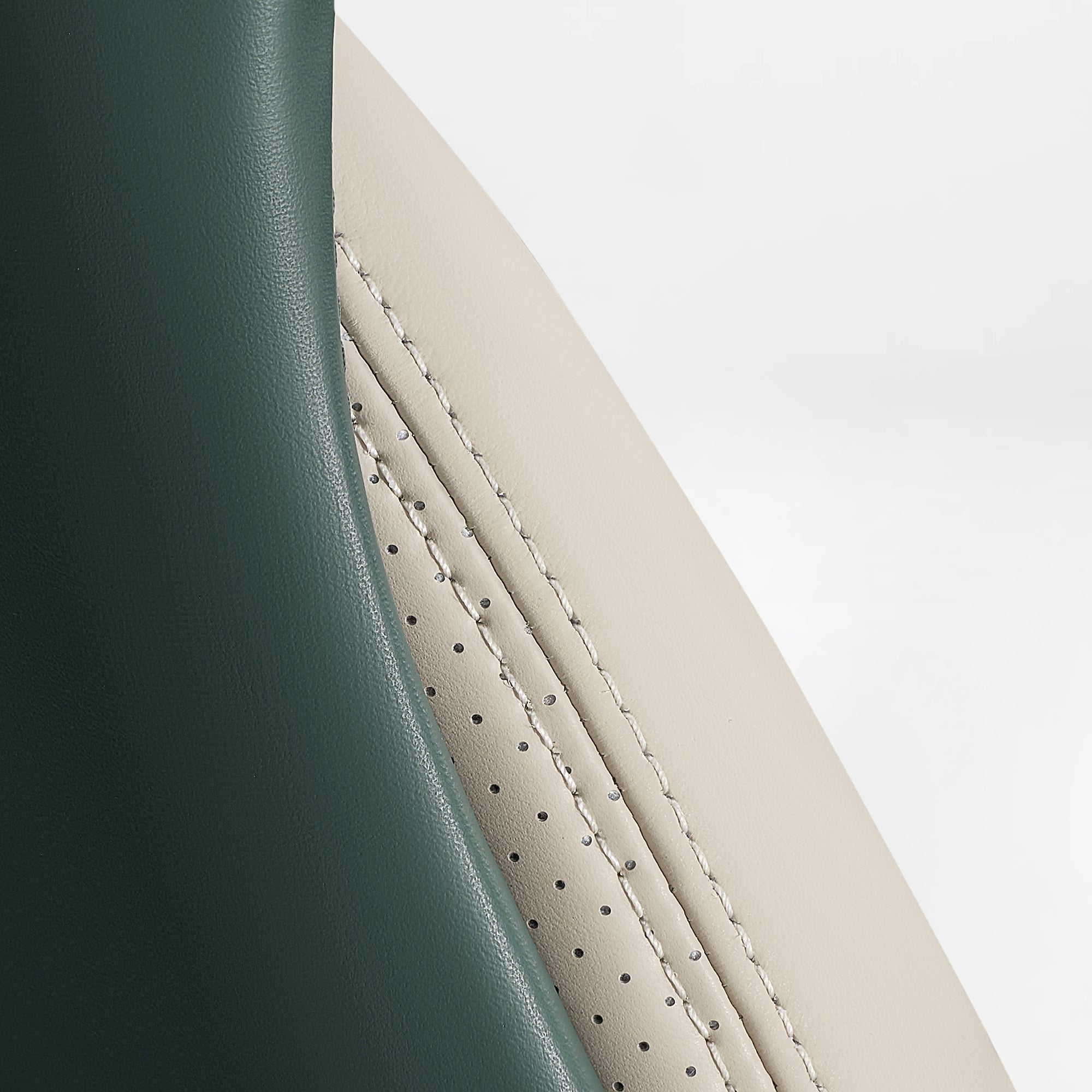 Eureka Ergonomic Serene executive chair side detail: forest green smooth leather meets cream perforated leather with contrast stitching.