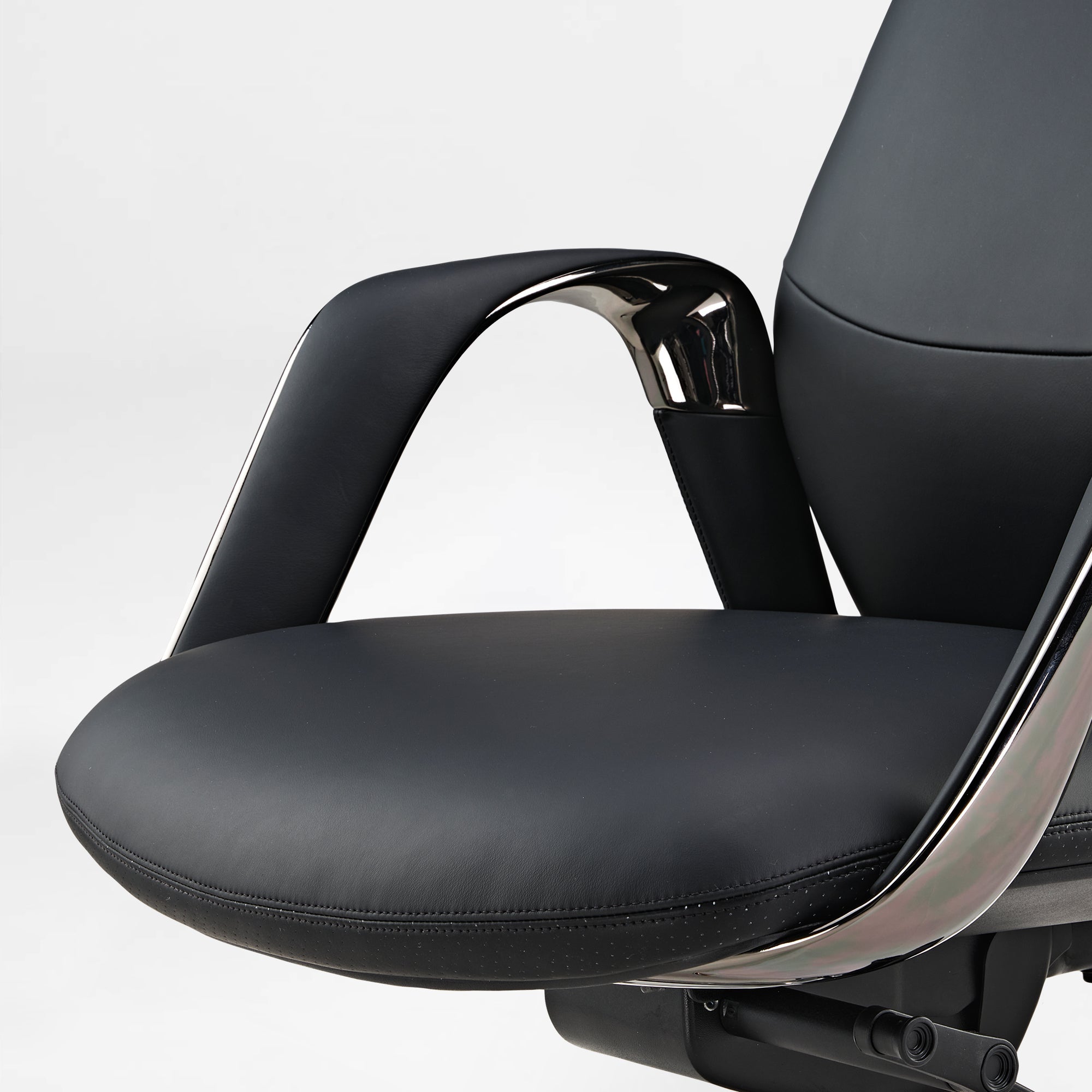 Eureka Ergonomic Serene black Napa leather executive chair armrest and perforated seat detail with chrome accents.