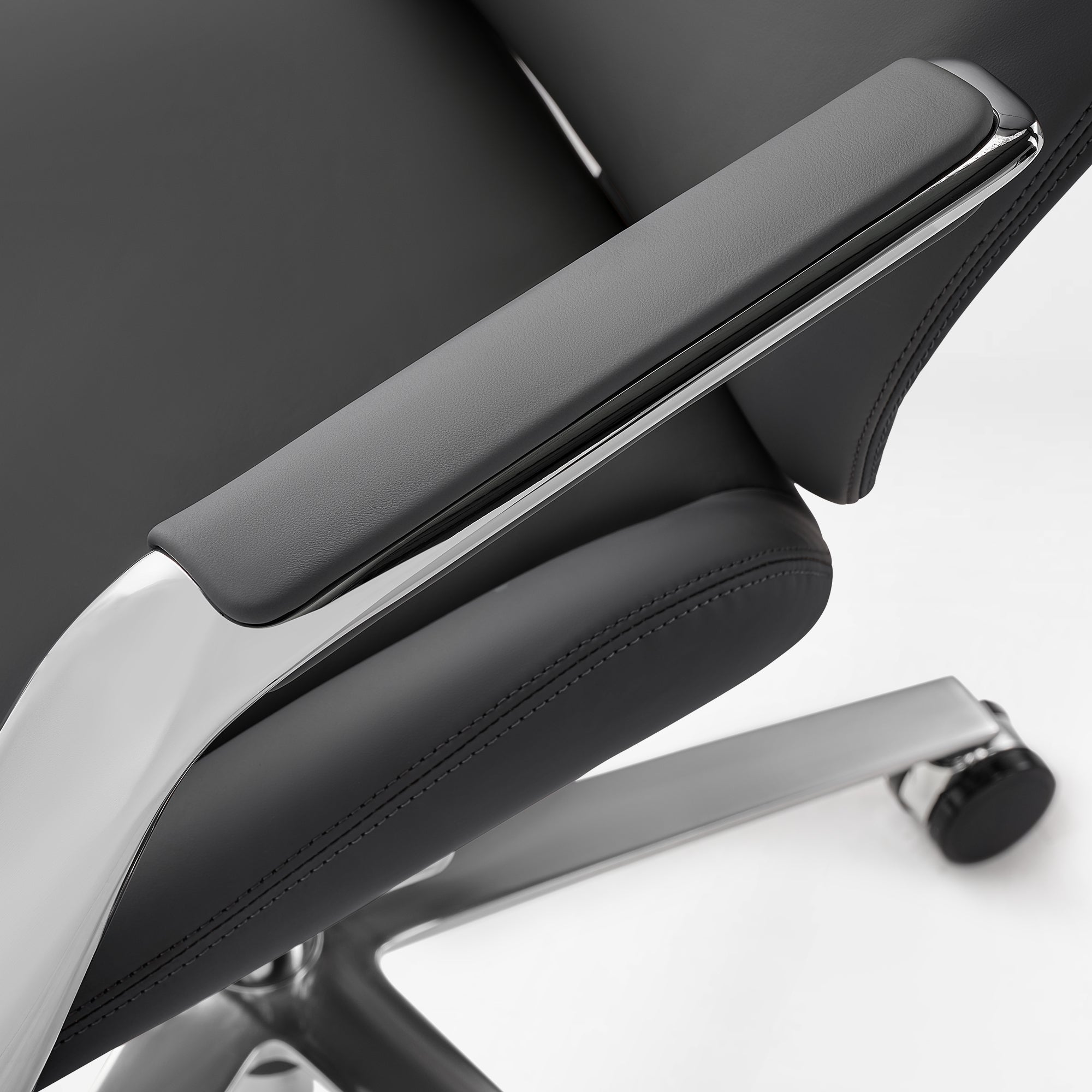 Eureka Ergonomic Serene Aaron black leather executive chair armrest close-up with chrome detail. Material and design focus.
