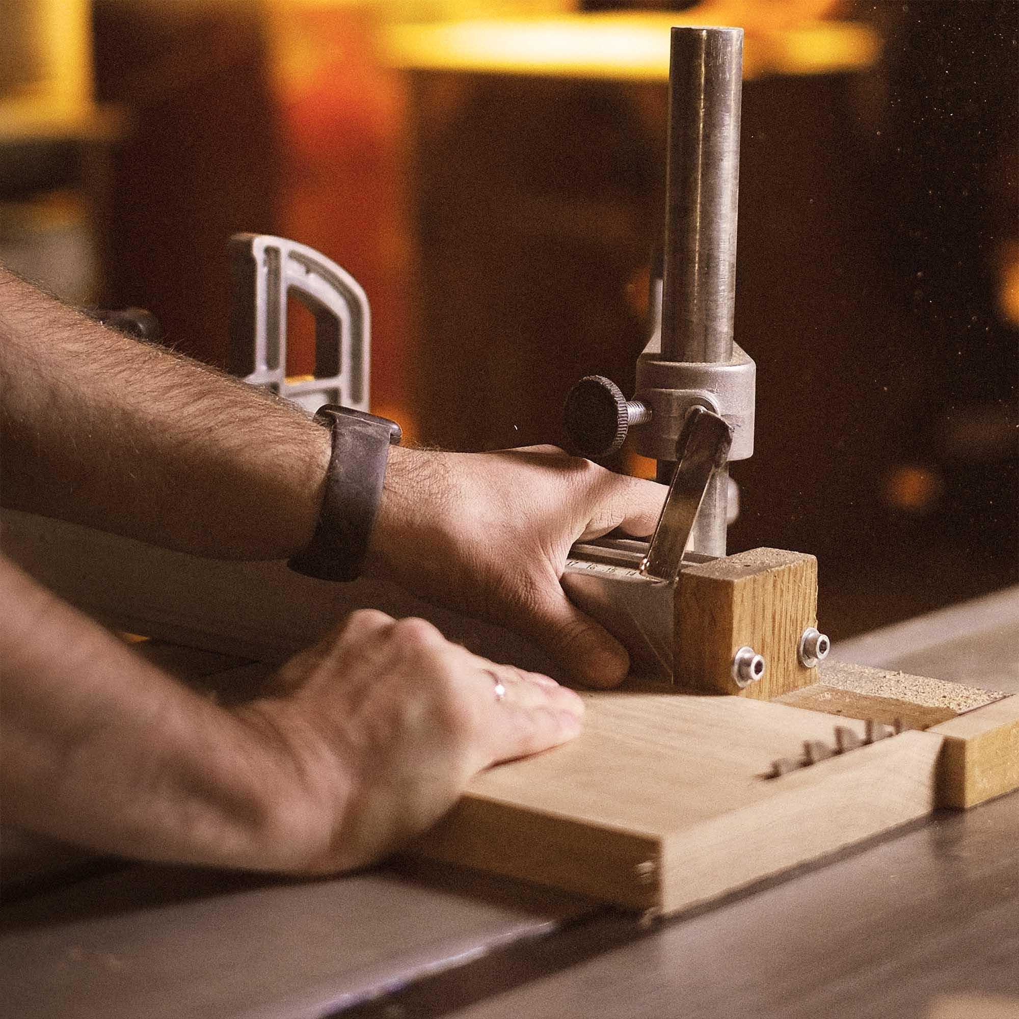 Craftsman Shaping Walnut Desk Component With Woodworking Machinery, Ark Pro Desk Production.