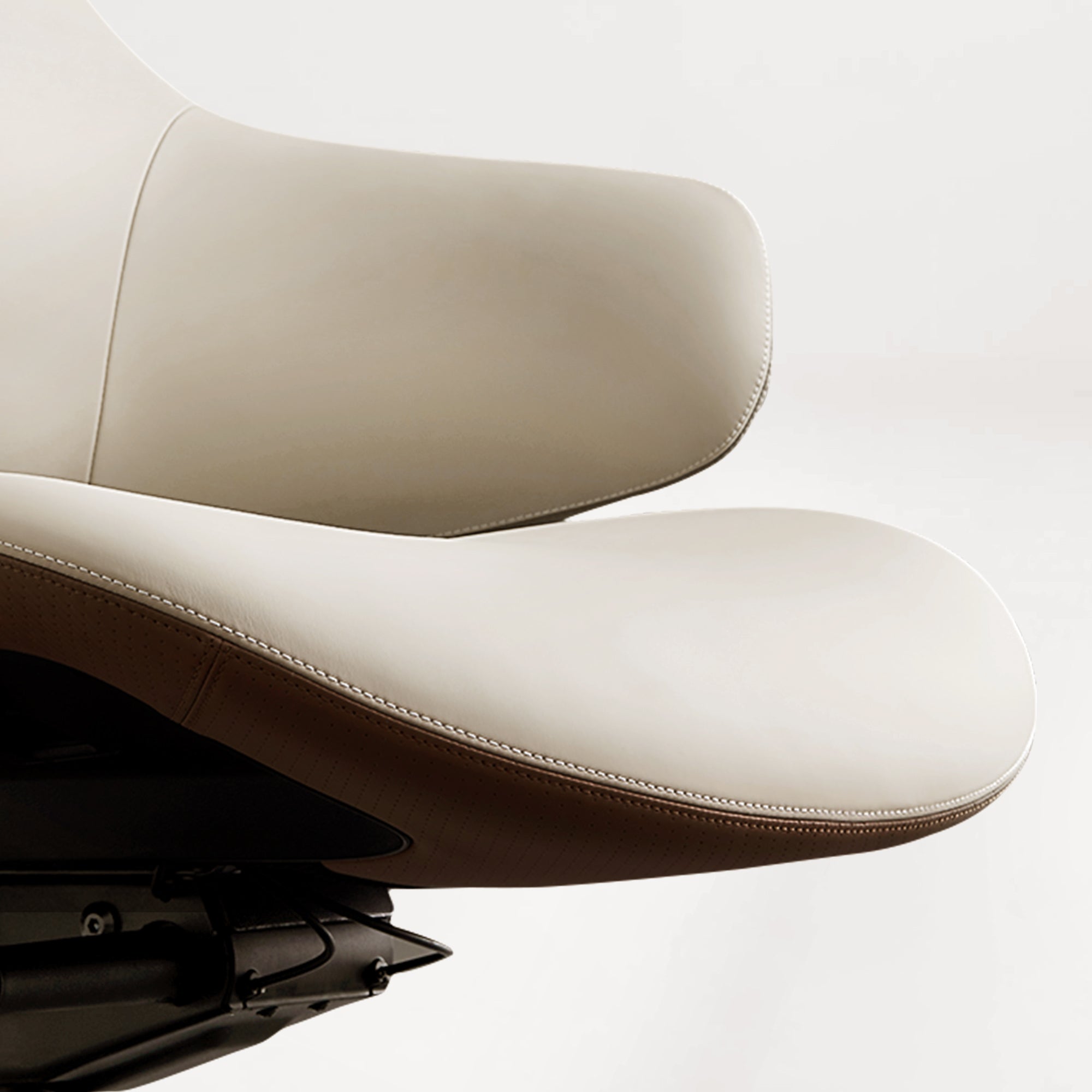 Eureka Ergonomic Close-up of cream Napa leather executive chair seat showing white stitching and perforated tan leather underside.